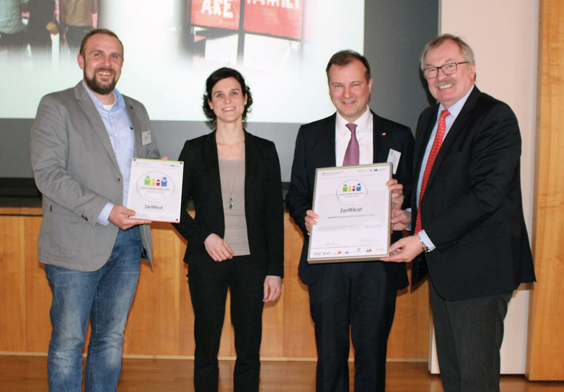 Vier Personen nehmen an einer Urkundenverleihung teil